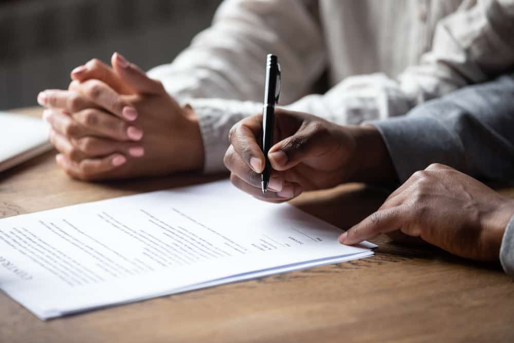 Close,Up,Of,African,American,Husband,Put,Signature,On,Contract